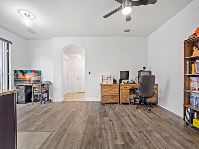 office with arched walkways, visible vents, a ceiling fan, and wood finished floors
