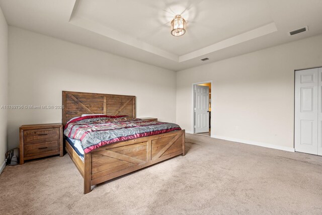 carpeted bedroom featuring visible vents, a raised ceiling, and baseboards