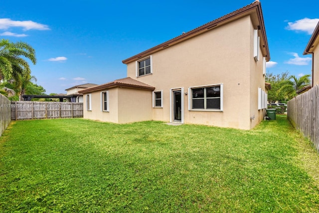 back of property with stucco siding, a yard, a tile roof, and a fenced backyard
