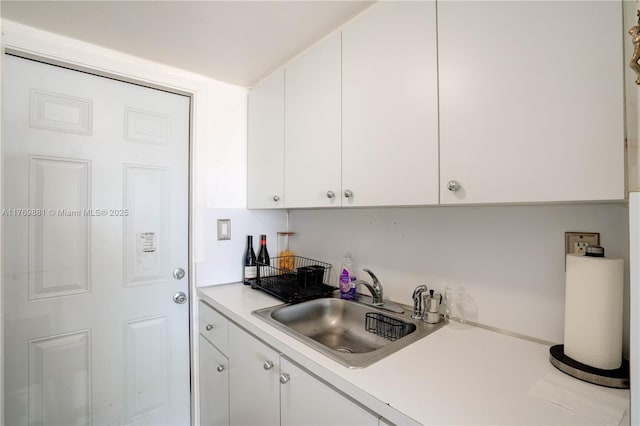 kitchen with white cabinetry, light countertops, and a sink
