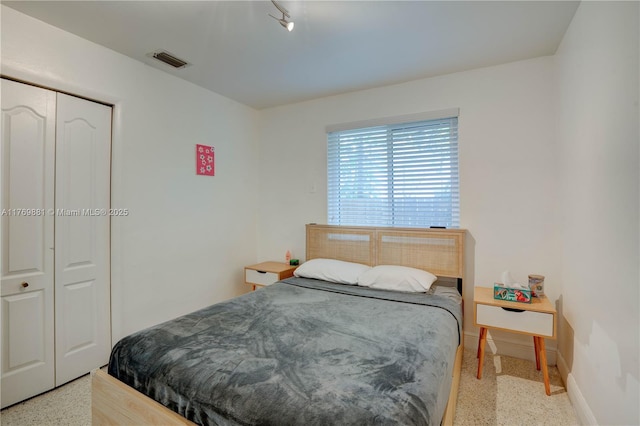 bedroom with baseboards, visible vents, a closet, and light speckled floor