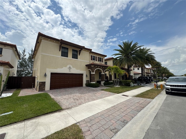 9840 NW 86th Ter, Doral, FL 33178 - mediterranean / spanish house with stone siding, fence, decorative driveway, an attached garage, and stucco siding