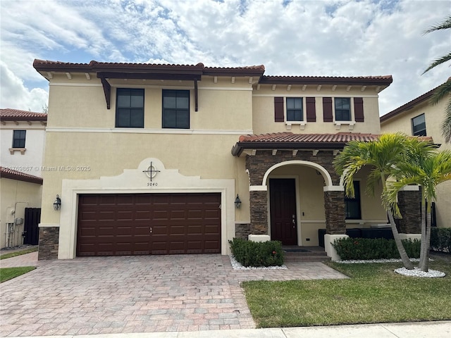 9840 NW 86th Ter, Doral, FL 33178 - mediterranean / spanish home with a tile roof, stone siding, stucco siding, an attached garage, and decorative driveway
