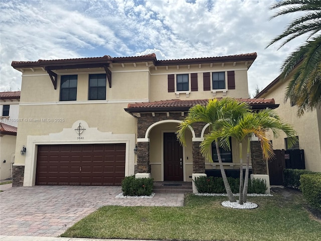 9840 NW 86th Ter, Doral, FL 33178 - mediterranean / spanish home with stone siding, stucco siding, a tiled roof, decorative driveway, and a garage