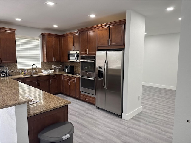 9840 NW 86th Ter, Doral, FL 33178 - kitchen featuring decorative backsplash, light stone countertops, stainless steel appliances, a sink, and light wood-type flooring