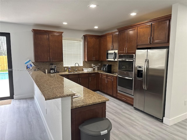 9840 NW 86th Ter, Doral, FL 33178 - kitchen with stainless steel appliances, light stone countertops, decorative backsplash, a sink, and a peninsula
