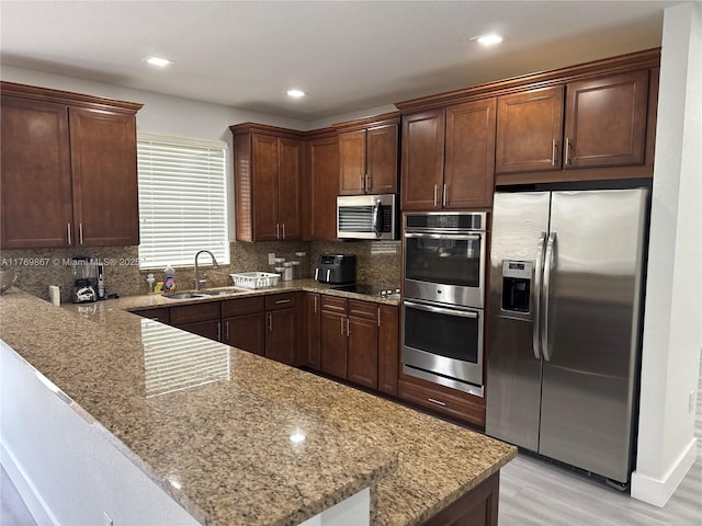 9840 NW 86th Ter, Doral, FL 33178 - kitchen featuring light stone counters, a sink, a peninsula, stainless steel appliances, and decorative backsplash