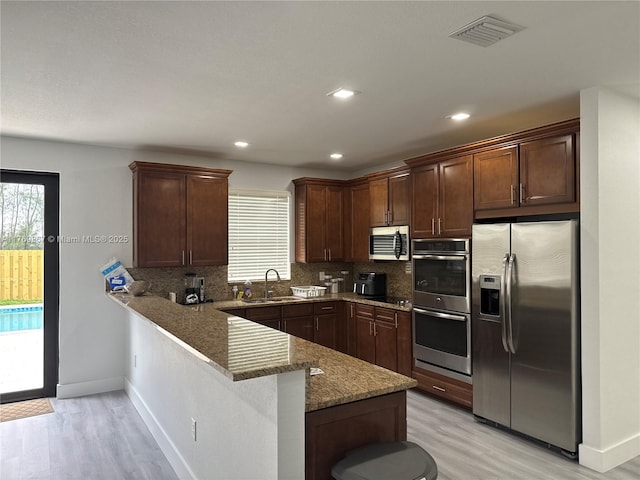 9840 NW 86th Ter, Doral, FL 33178 - kitchen featuring a sink, tasteful backsplash, appliances with stainless steel finishes, a peninsula, and visible vents