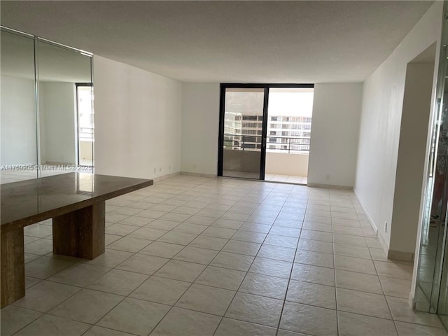 empty room with baseboards, a textured ceiling, a wealth of natural light, and light tile patterned floors