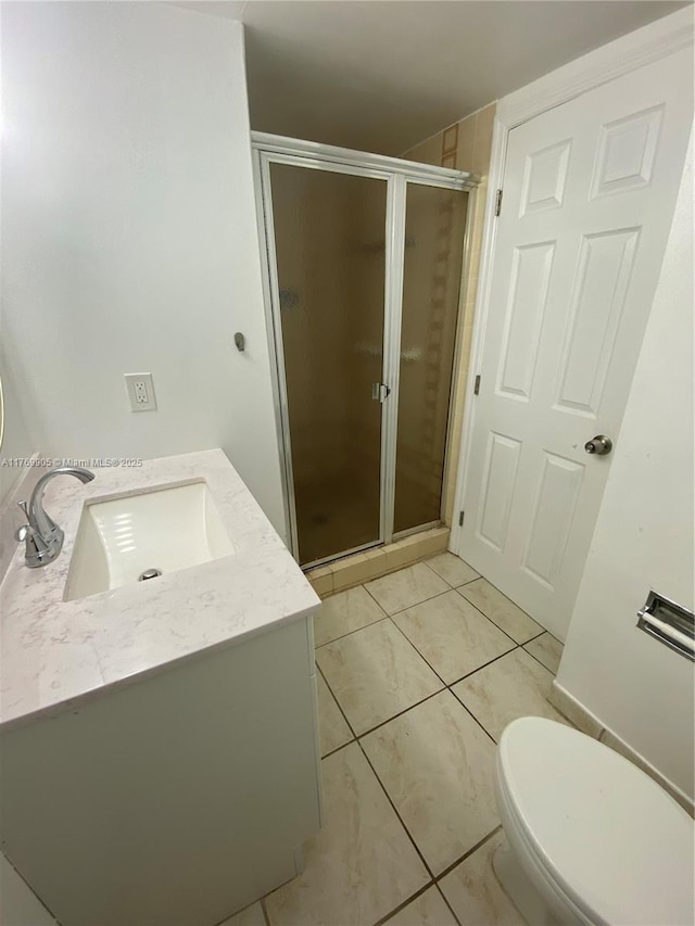 bathroom featuring tile patterned flooring, vanity, toilet, and a shower stall