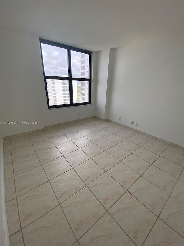empty room with baseboards and light tile patterned floors