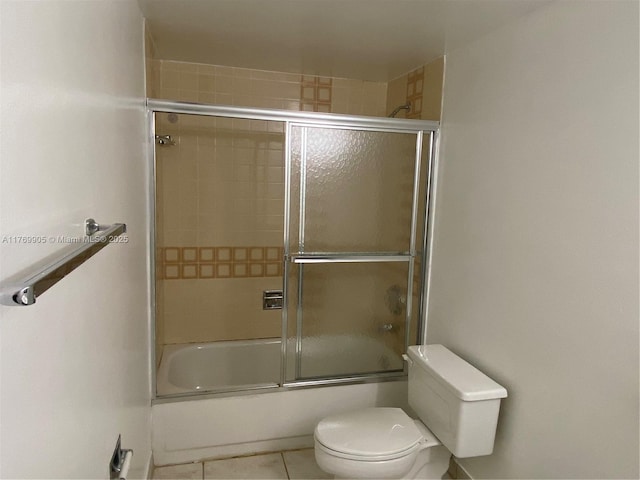 bathroom featuring tile patterned floors, toilet, and shower / bath combination with glass door