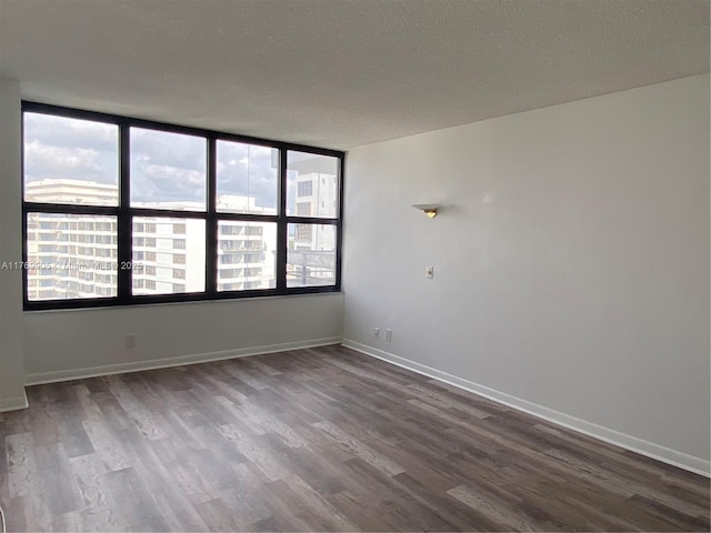 empty room with dark wood finished floors, baseboards, and a textured ceiling
