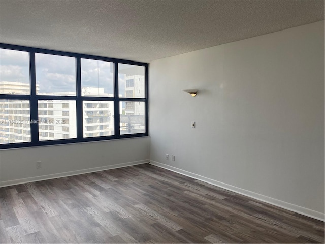 spare room with baseboards, dark wood-style flooring, and a textured ceiling