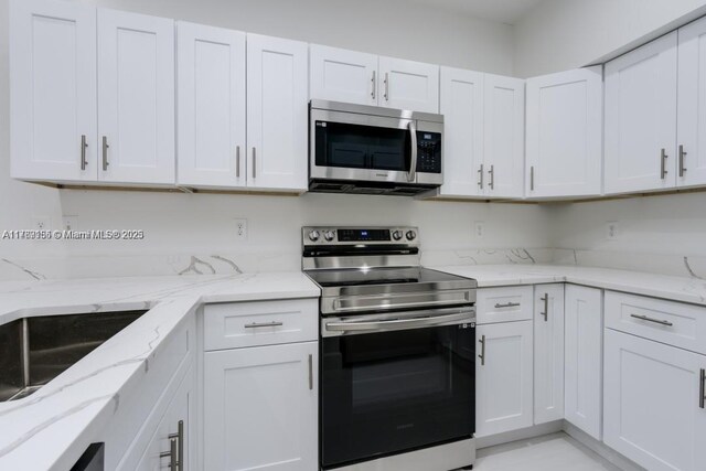 4834 NW 58th Mnr, Coconut Creek, FL 33073 - kitchen featuring white cabinetry, light stone countertops, a sink, and stainless steel appliances