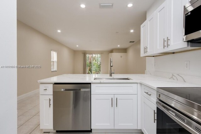 4834 NW 58th Mnr, Coconut Creek, FL 33073 - kitchen with light stone counters, a sink, a peninsula, stainless steel appliances, and white cabinets