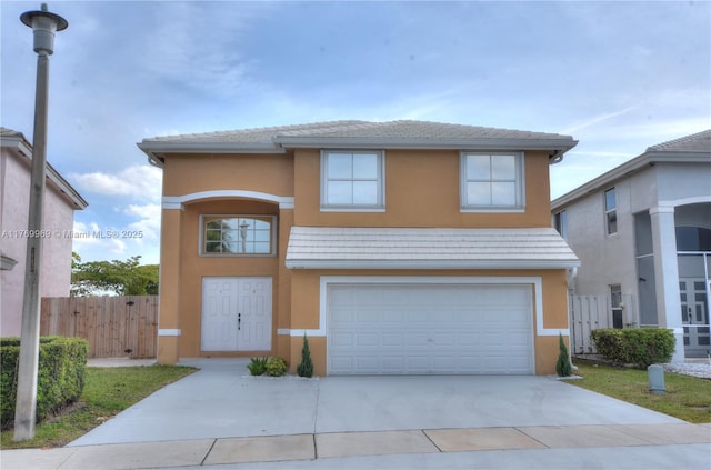 view of front of property featuring stucco siding, driveway, a garage, and fence