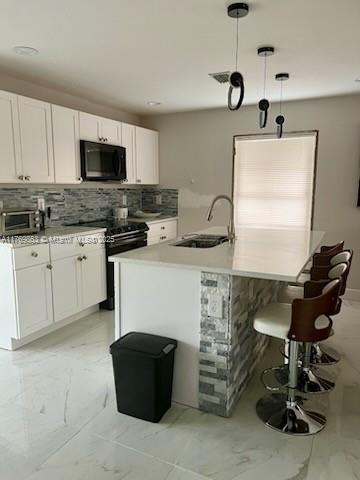 kitchen with a sink, black microwave, white cabinetry, range with electric cooktop, and marble finish floor