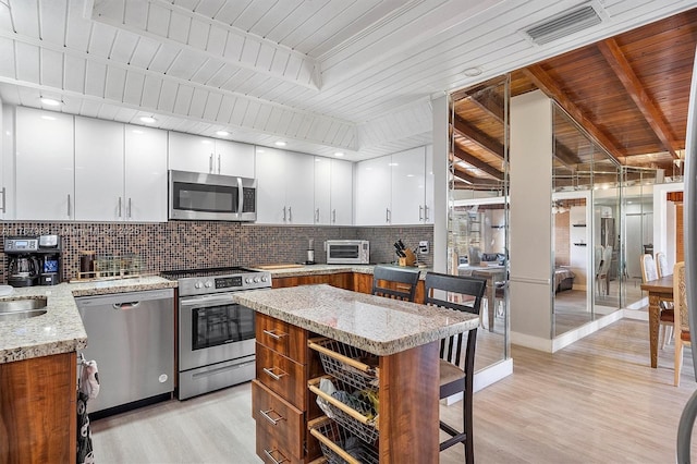 881 Hialeah Dr, Hialeah, FL 33010 - kitchen featuring stainless steel appliances, decorative backsplash, light wood-style flooring, a wood ceiling with exposed beams, and white cabinets