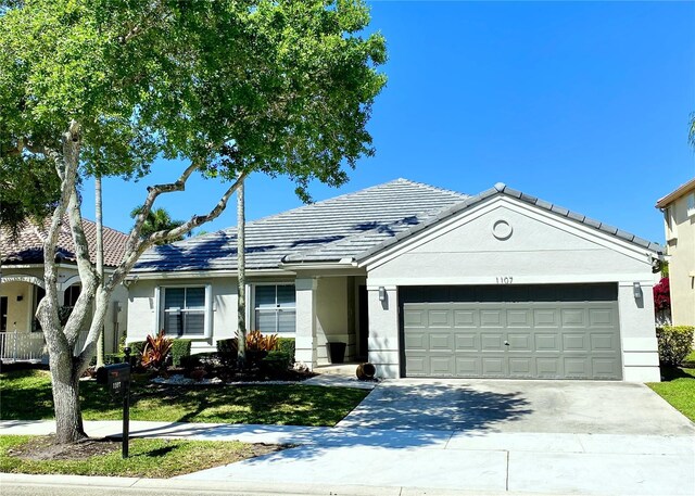 ranch-style home with a tiled roof, a garage, driveway, and stucco siding