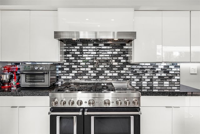 kitchen with stainless steel refrigerator with ice dispenser, a peninsula, white microwave, white cabinetry, and decorative backsplash