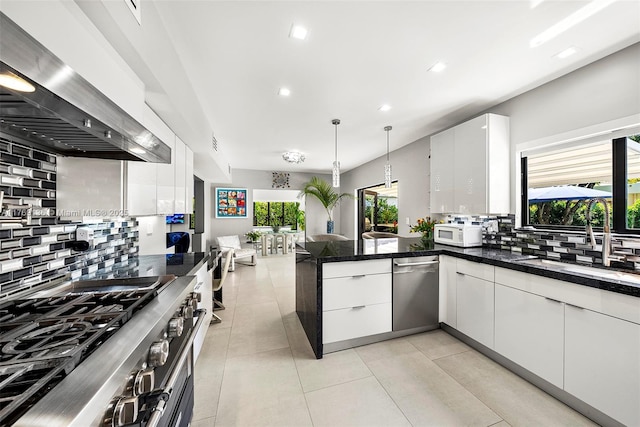 kitchen with modern cabinets, a peninsula, dark countertops, stainless steel appliances, and backsplash