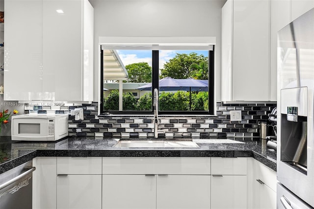 kitchen with visible vents, white cabinets, dark countertops, a peninsula, and stainless steel appliances