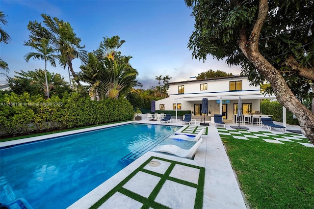 pool at dusk with a patio area and a fenced in pool