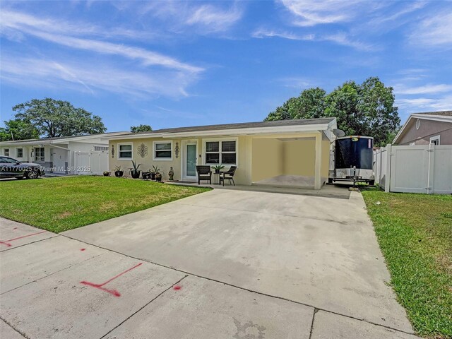 ranch-style house featuring stucco siding, fence, driveway, a front yard, and a gate
