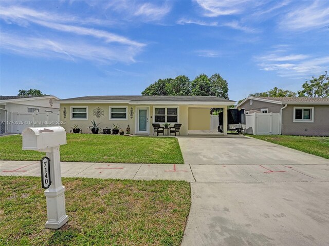 ranch-style house featuring fence, concrete driveway, a front yard, an attached carport, and stucco siding