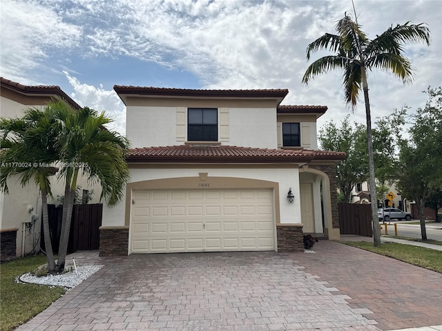 10086 NW 89th Ter, Doral, FL 33178 - mediterranean / spanish-style house featuring stone siding, decorative driveway, fence, and an attached garage