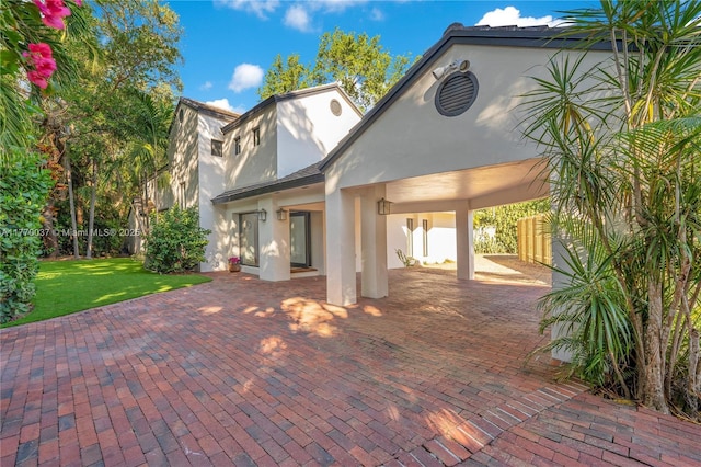 back of house with a lawn, stucco siding, and fence