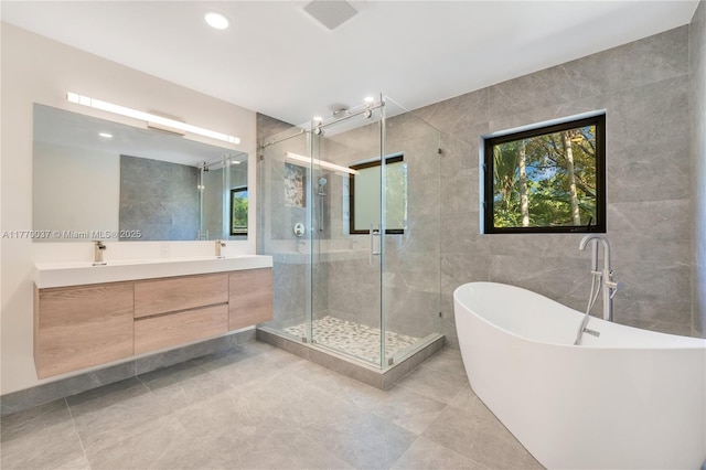 bathroom featuring a freestanding bath, double vanity, a stall shower, and tile walls