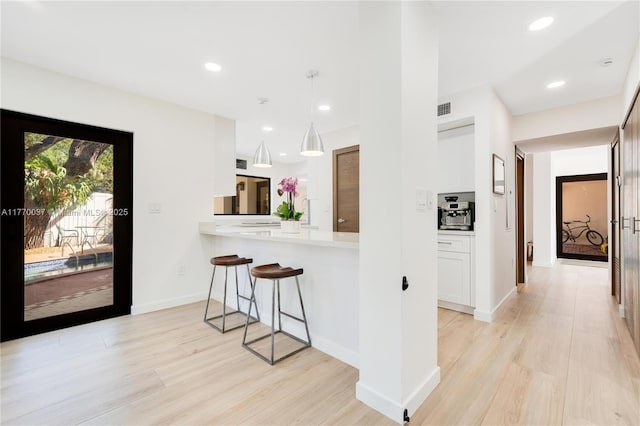 kitchen with a kitchen breakfast bar, recessed lighting, light wood-style floors, and visible vents