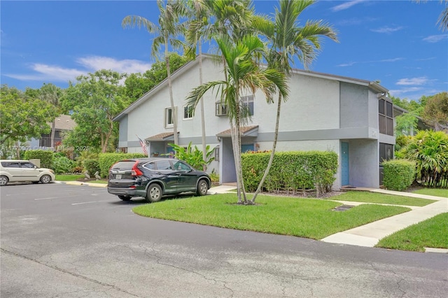 2761 S Oakland Forest Dr Unit 201, Oakland Park, FL 33309 - view of side of home featuring stucco siding, uncovered parking, and a yard