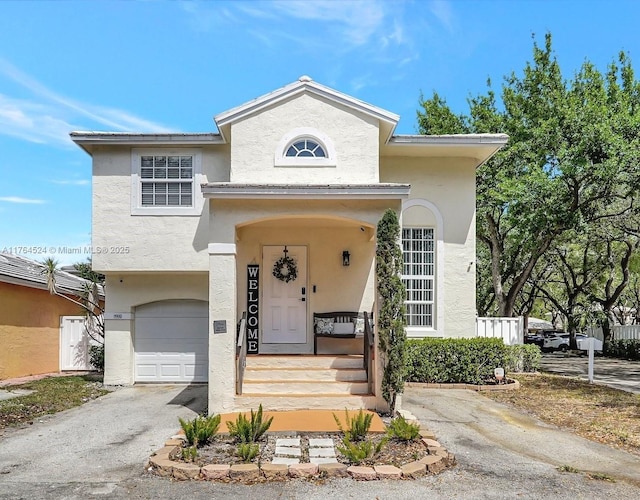 view of front facade with stucco siding, an attached garage, and aphalt driveway