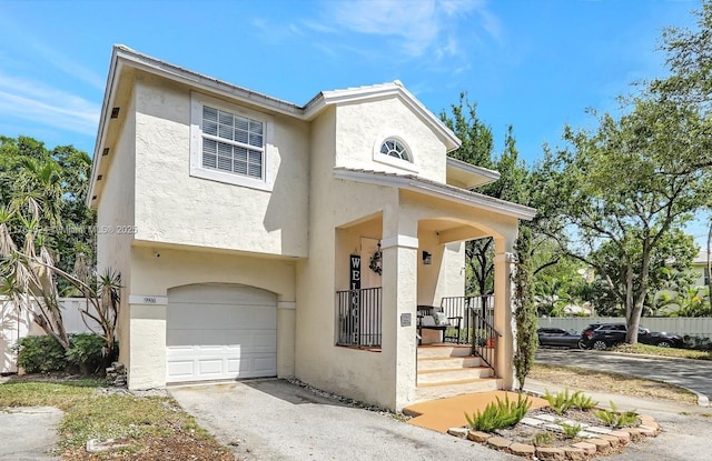 view of front facade with a porch, driveway, stucco siding, and an attached garage