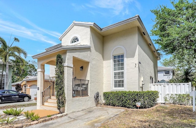 view of front of house featuring a porch, stucco siding, and fence