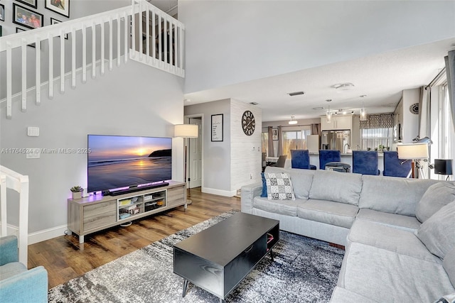 living area with stairs, a high ceiling, wood finished floors, and baseboards