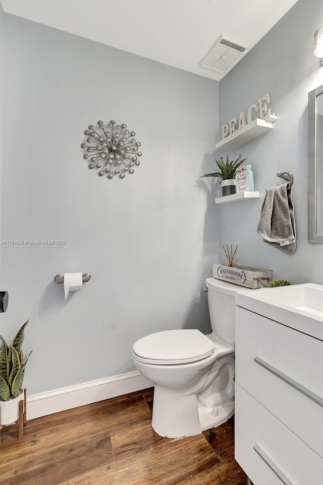 bathroom with visible vents, baseboards, toilet, wood finished floors, and vanity