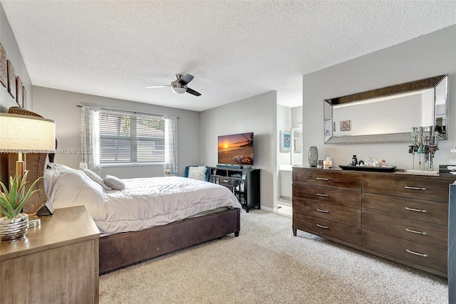 bedroom with light carpet, connected bathroom, ceiling fan, and a textured ceiling