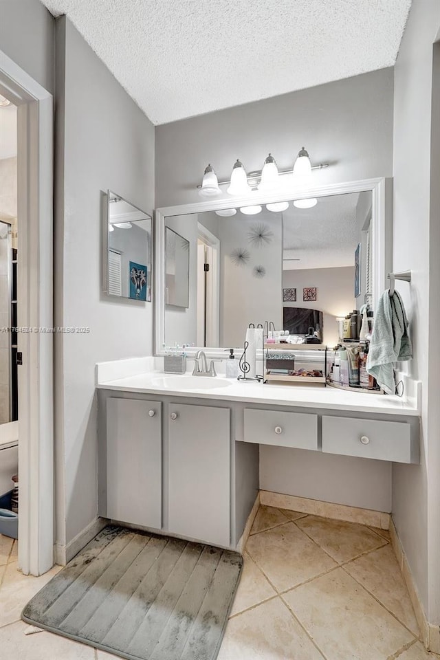 bathroom with tile patterned floors, toilet, vanity, a textured ceiling, and baseboards