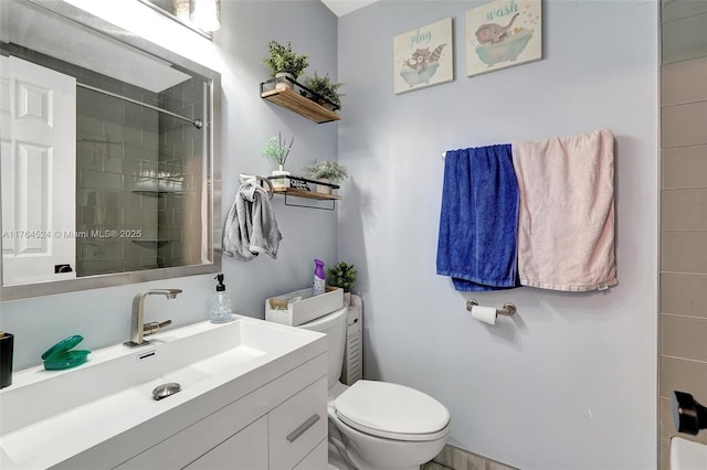 full bathroom with toilet, a tile shower, and vanity