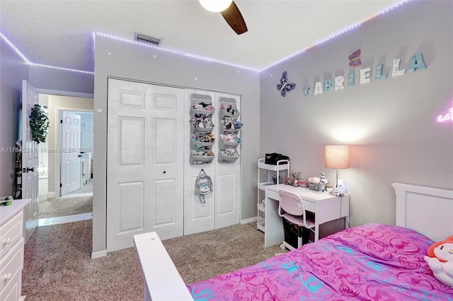bedroom with a closet, carpet floors, a textured ceiling, visible vents, and ceiling fan