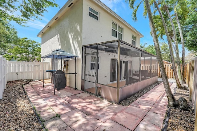 back of house featuring a fenced backyard, stucco siding, and a sunroom