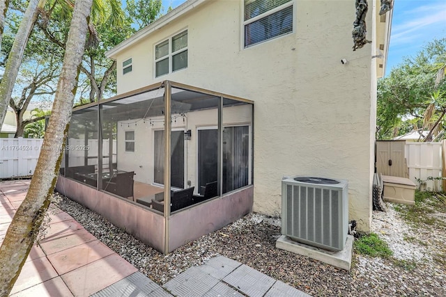 back of house featuring stucco siding, central air condition unit, and fence