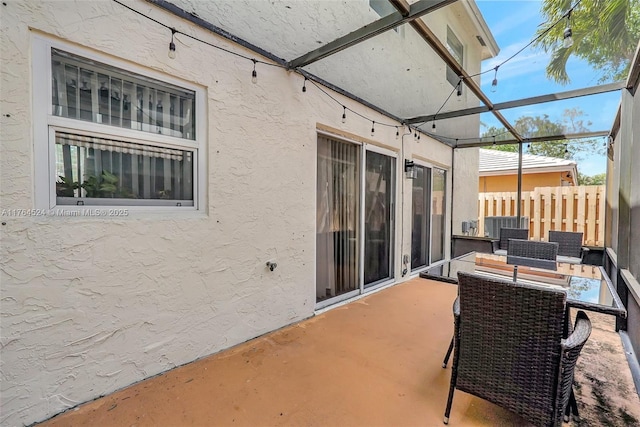 view of patio with glass enclosure and fence