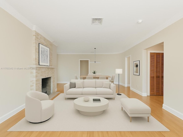 living room featuring visible vents, ornamental molding, wood finished floors, baseboards, and a tile fireplace