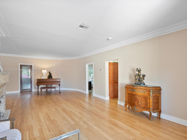 living area with crown molding, a wealth of natural light, light wood-type flooring, and visible vents