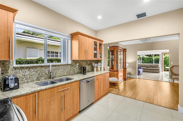 kitchen with a sink, stainless steel dishwasher, backsplash, and visible vents